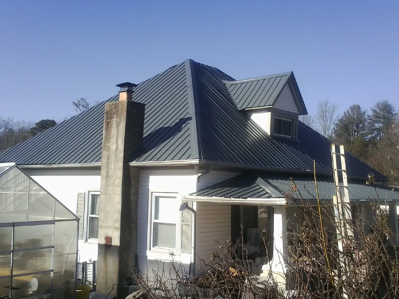 Dark blue standing seam metal roof on a white farmhouse with dormer — Slate & Tile Roof Repair by Roofing Brothers in Cerulean