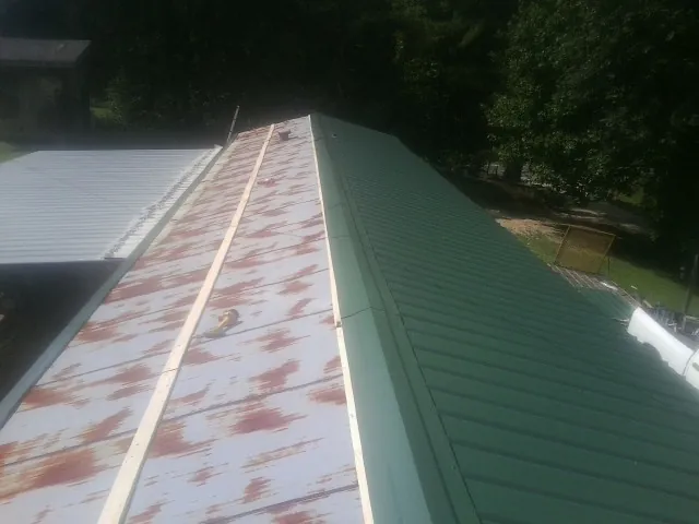 Old rusted panels beside newly installed green metal roofing — Wind Damage Roof Repair by Roofing Brothers in Cerulean