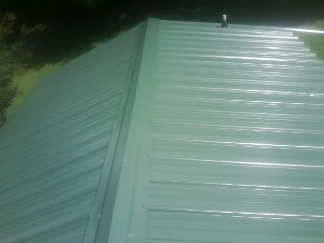 New green metal panels meeting at the ridge of a roof — Flat Roof Repair work by our crew in Cerulean