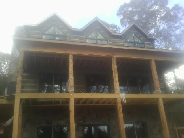 Dormers and porch framing on a large log home under construction — Roof Coating work by our crew in Cerulean