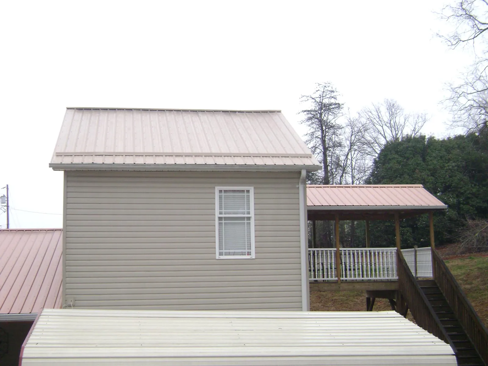 Tan metal roofs on a two story addition and attached porch, from a Roof Replacement job in Cerulean